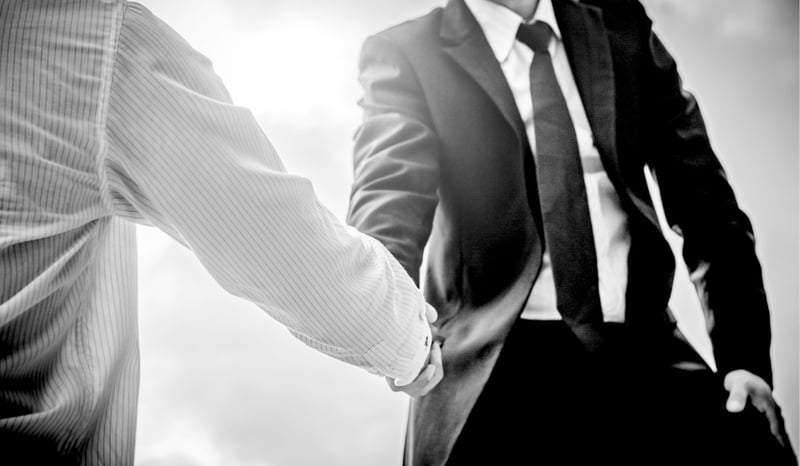 two businessmen shaking heads with sun glare in background