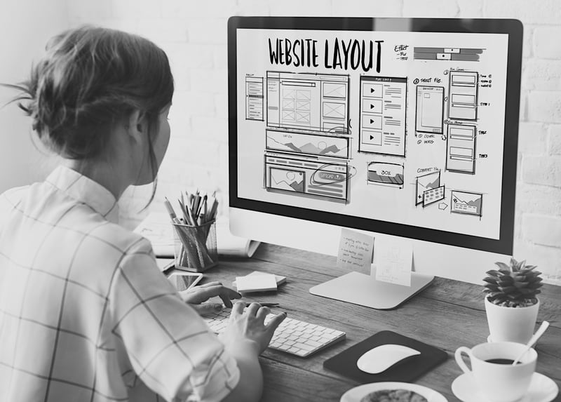 woman at desk looking at website design layout on computer screen