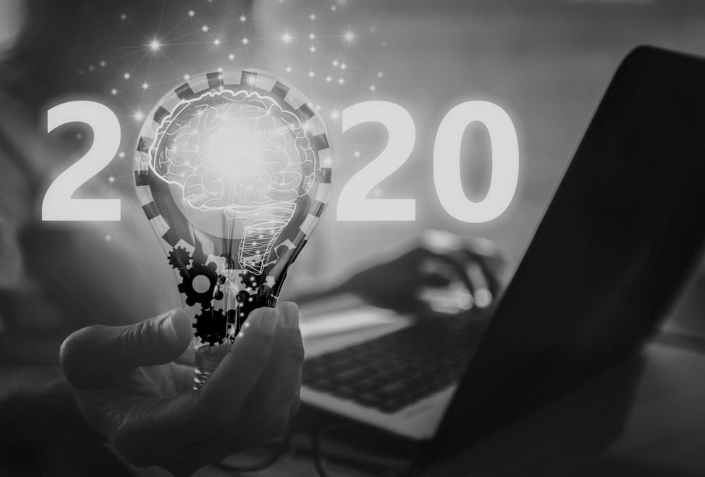 marketer using laptop and holding light bulb with 2020 displayed