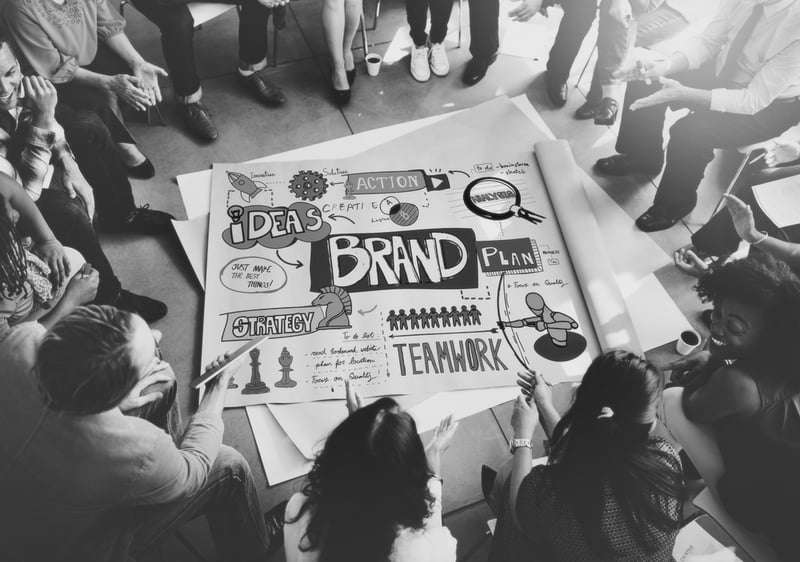 business team brainstorming brand ideas in a circle with large paper at the center