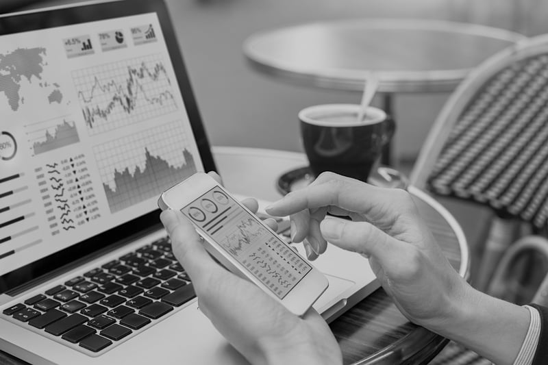 hand with phone and laptop screen displaying marketing analytics data