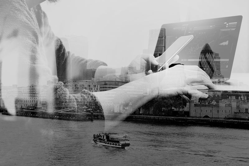 person on phone and computer projected over a city with a ferry boat on a bay