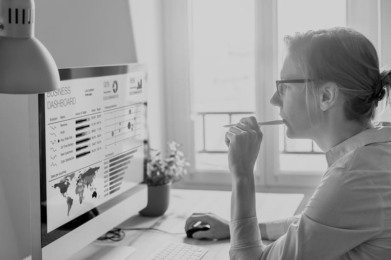 marketing woman with glasses and pen reviewing website performance analytics on computer