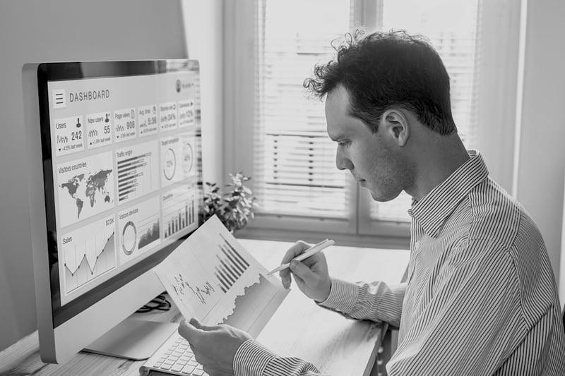 marketer reviewing metrics report and data on paper and computer screen