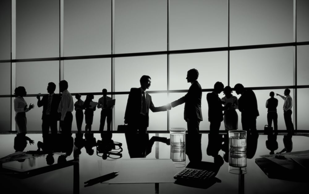 group of marketers at a conference in front of glass window and desk with cups of water and calculator