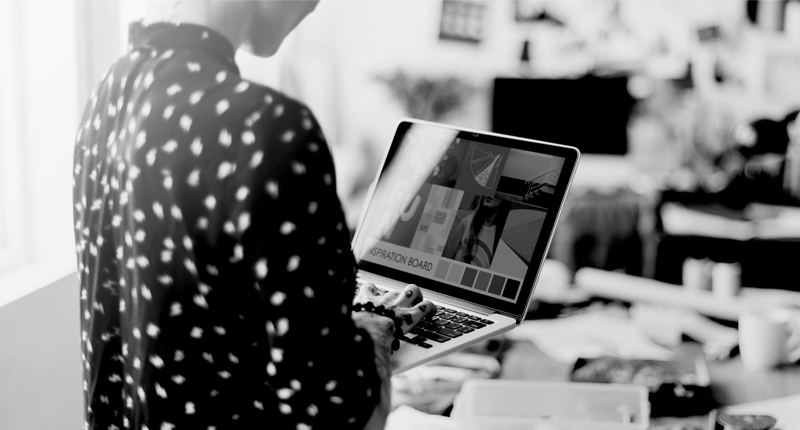 Web designer standing in office with laptop in hand