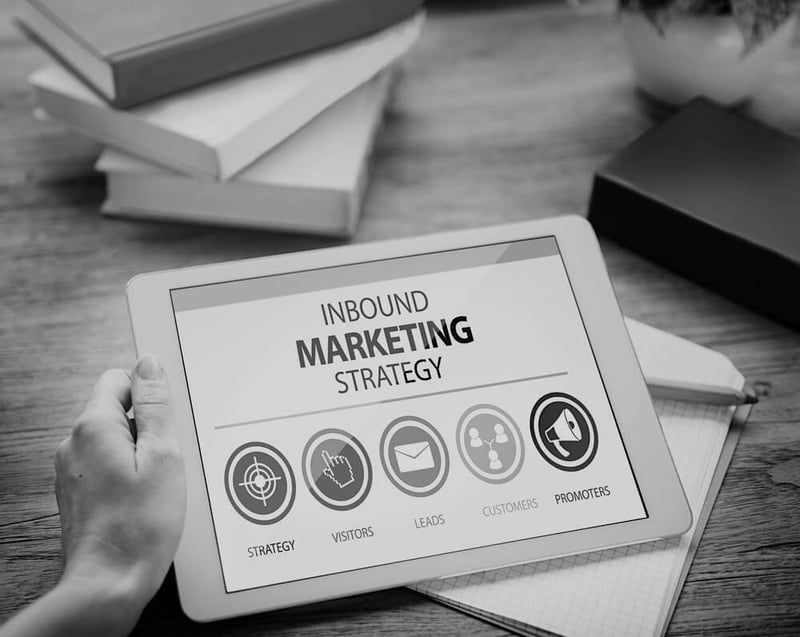 person at cluttered desk with tablet with inbound marketing strategy displayed on screen