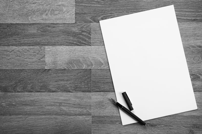 blank piece of paper with a pen on a wooden desk