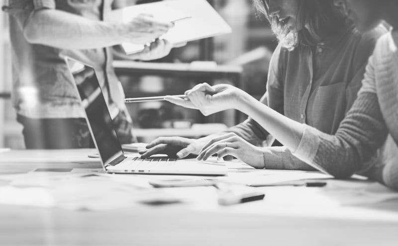 marketer using pen to point at laptop screen on desk